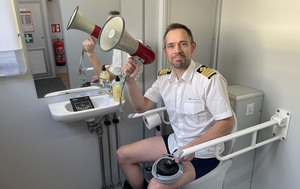 Skipsfører Sindre Helmersen sittende på toalett med buksa på anklene og megafon