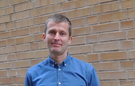 Christian Lupke foran murvegg