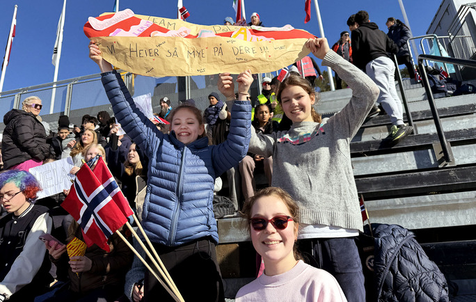 Jenter på tribune i Holmenkollen med flagg og plakat