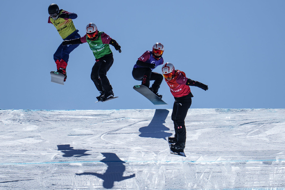 Fire personer står på snowboard og hopper