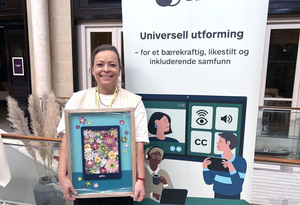 Kristine Magnesen smiler og holder innrammet bilde