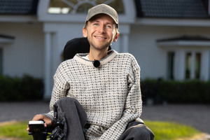 Daniel Maudal i elektrisk rullestol foran hvitt hus