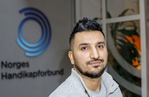 Portrettfoto av Siavash Mobasheri foran en vegg med Norges Handikapforbunds logo.