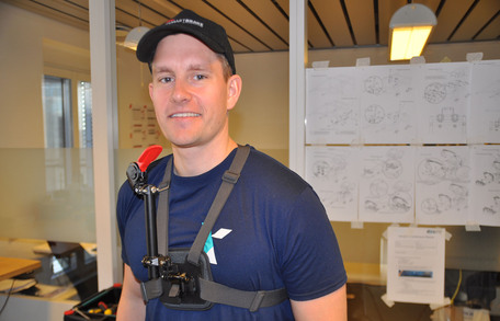 Bendik Fon står i kontorlokale med hakebrems festet til overkroppen