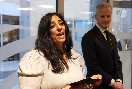 Lubna Jaffery taler i Norges Handikapforbunds lokaler, Jonas Gahr Støre lytter i bakgrunnen.