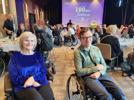 Toril Kvaløsæter og Jørgen Johansen i rullestoler foran andre jubileumsgjester samlet til middag
