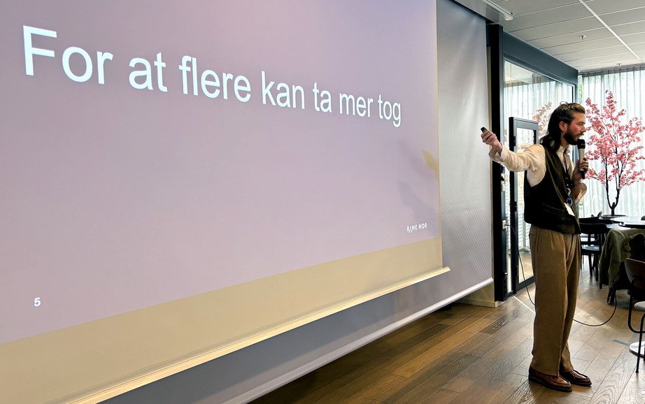 Mann peker på storskjerm med teksten 