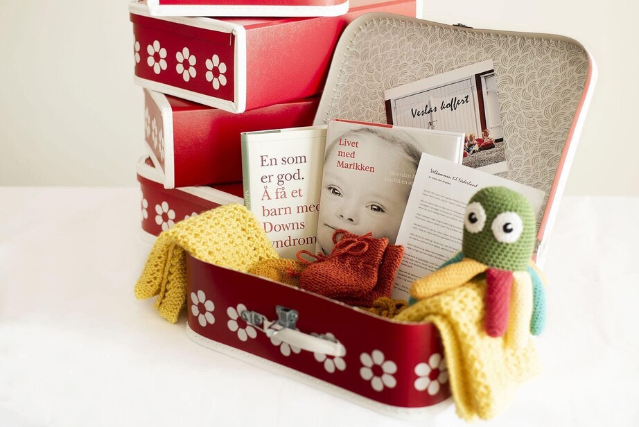 Rød barnekoffert med klær, kosedyr og informasjon