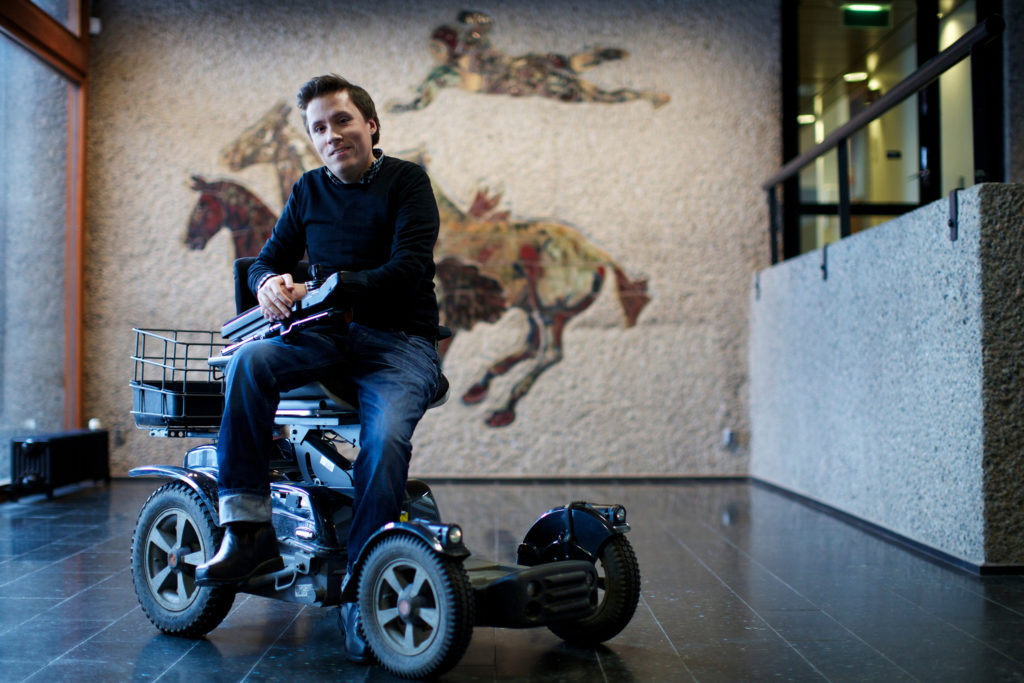 Jan Grue poserer på en elektrisk rullestol.