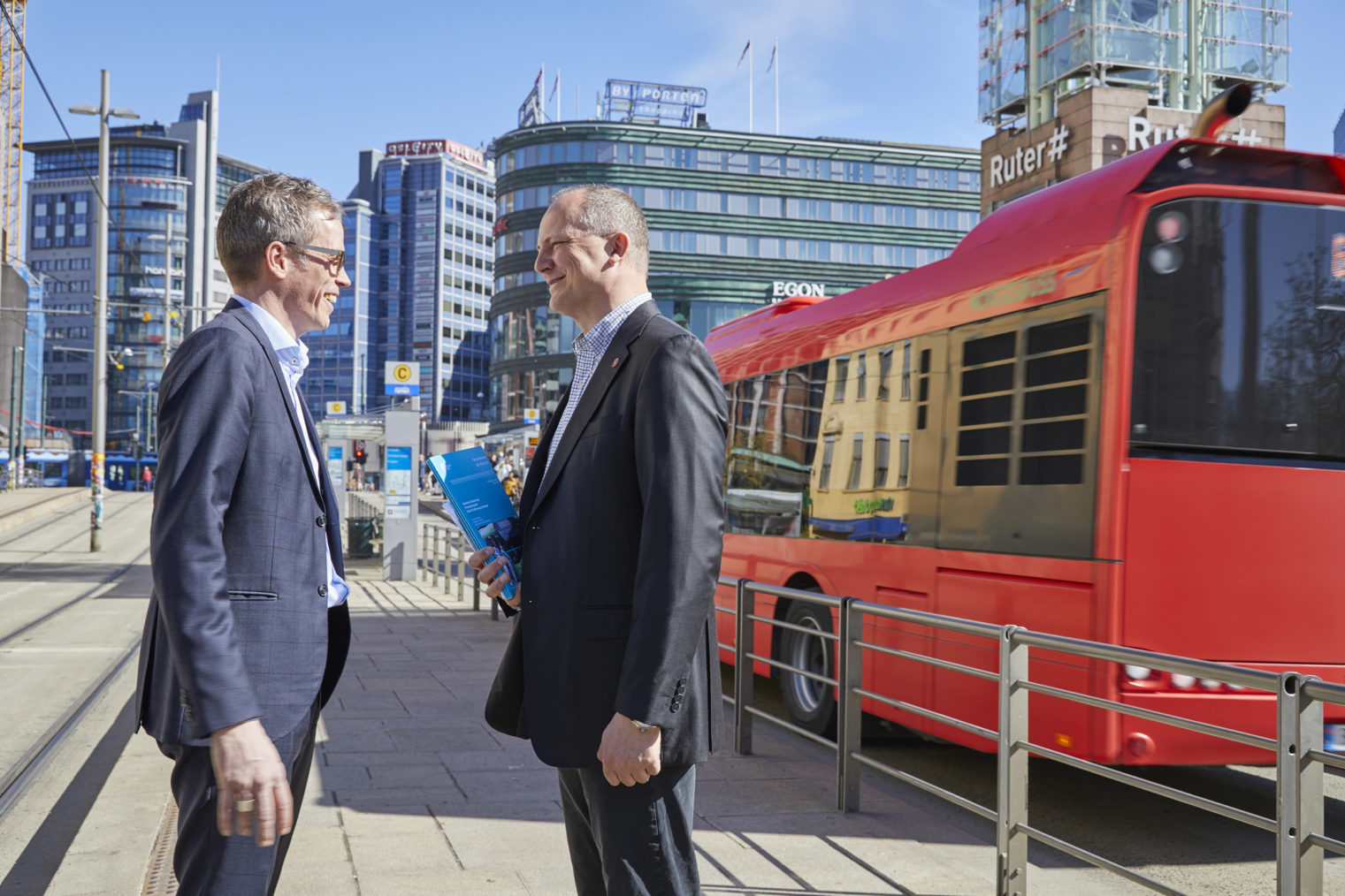 Mehus og Solvik-Olsen ansikt til ansikt på Jernbanetorget med busser og trikkeskinner i bakgrunnen.