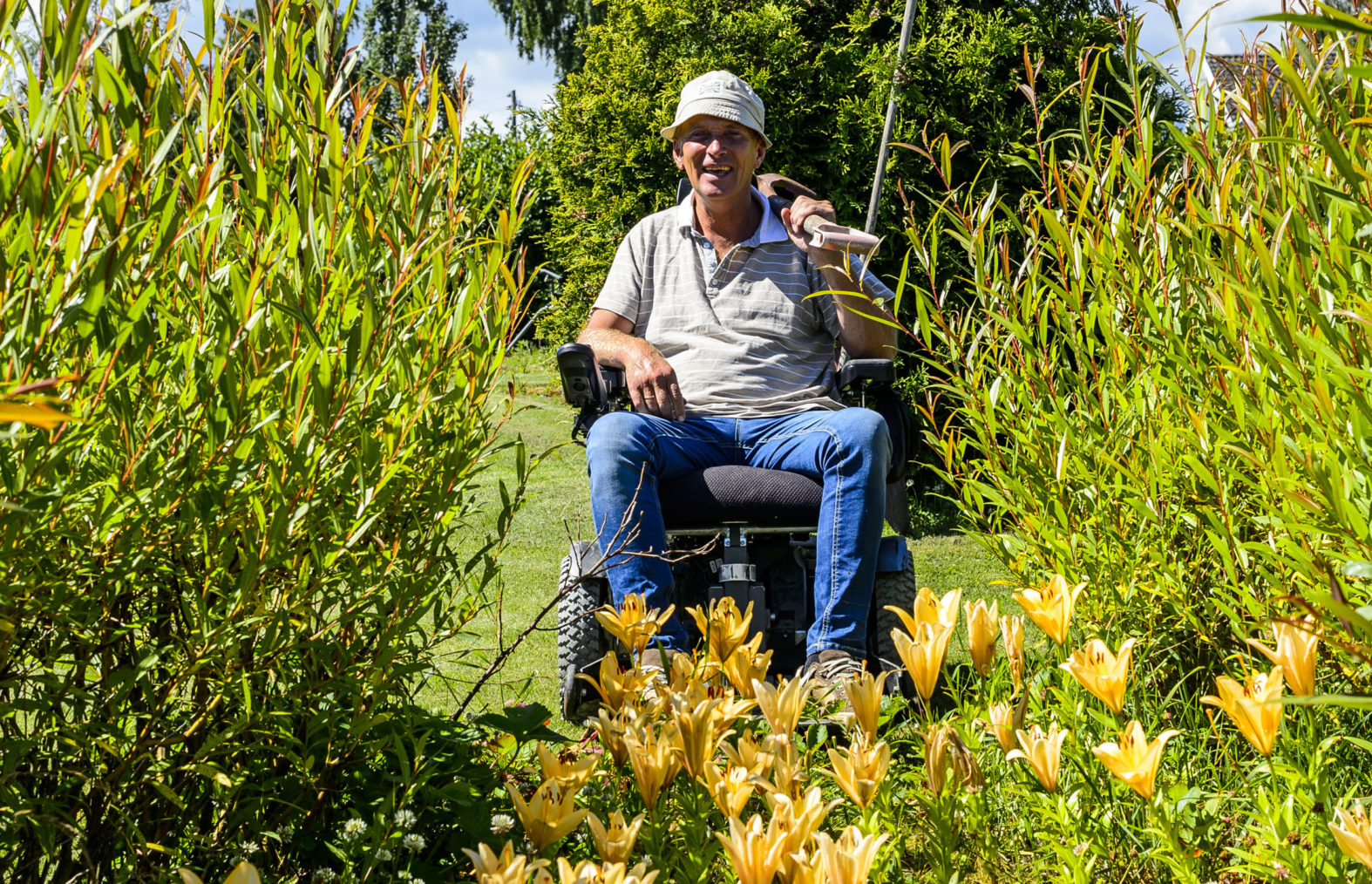 Heine fotografert i rullestol mellom planter og blomster.