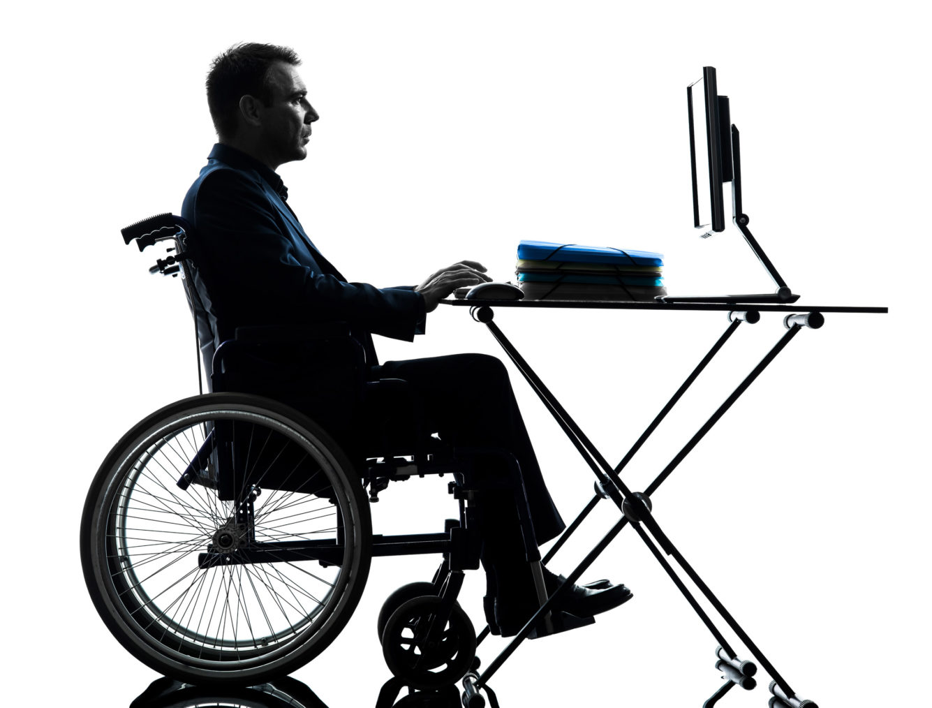 Mannsperson i rullestol sitter og jobber med pc-skjerm.