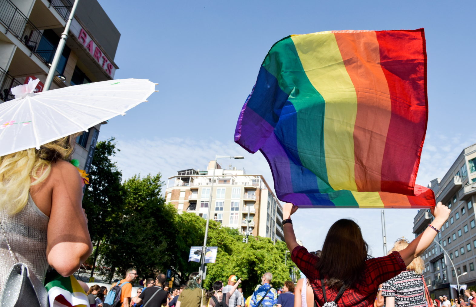 Bilde fra parade der kvinne vaier med et regnbueflagg.