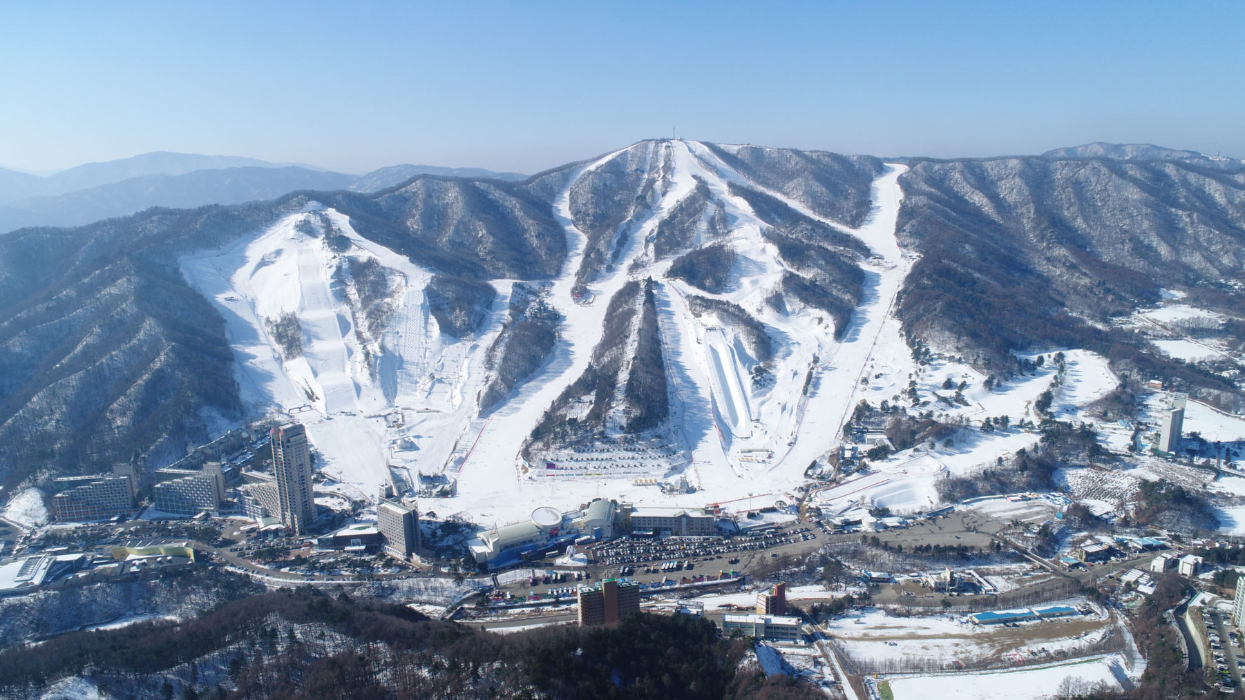 Dronebilde som viser Pyeongchang ovenfra, med alpintbakkene i bakgrunnen.