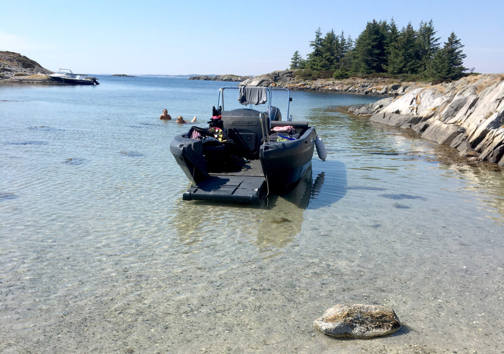 Båten kjørt inn på en strand med baugen åpen ut mot vannet.