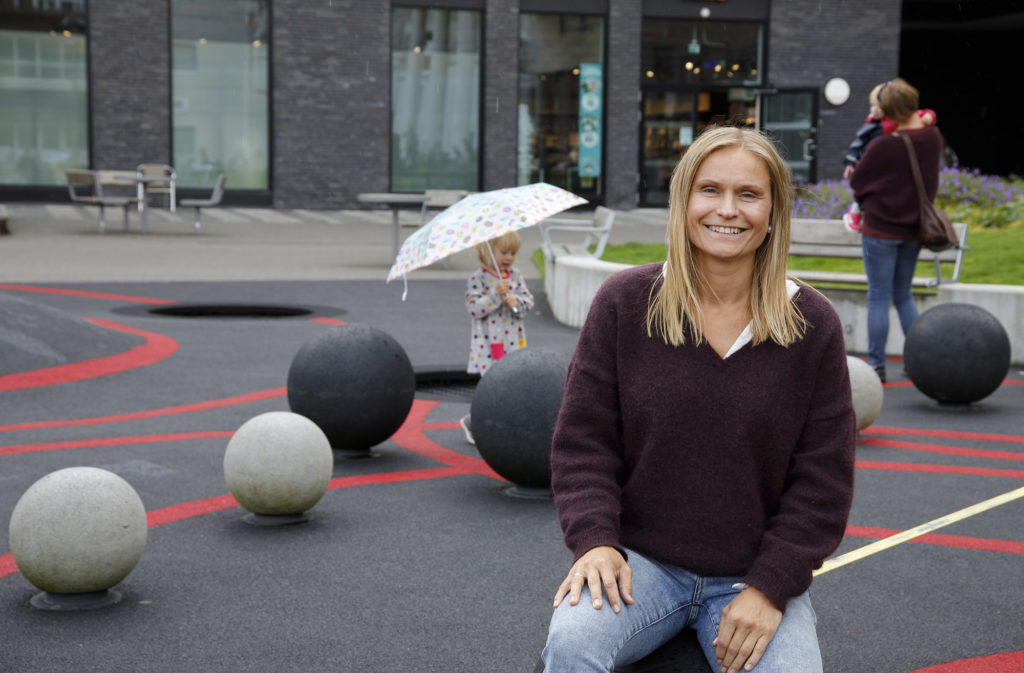 Maria sitter på en av kulene. I bakgrunnen leker et barn.