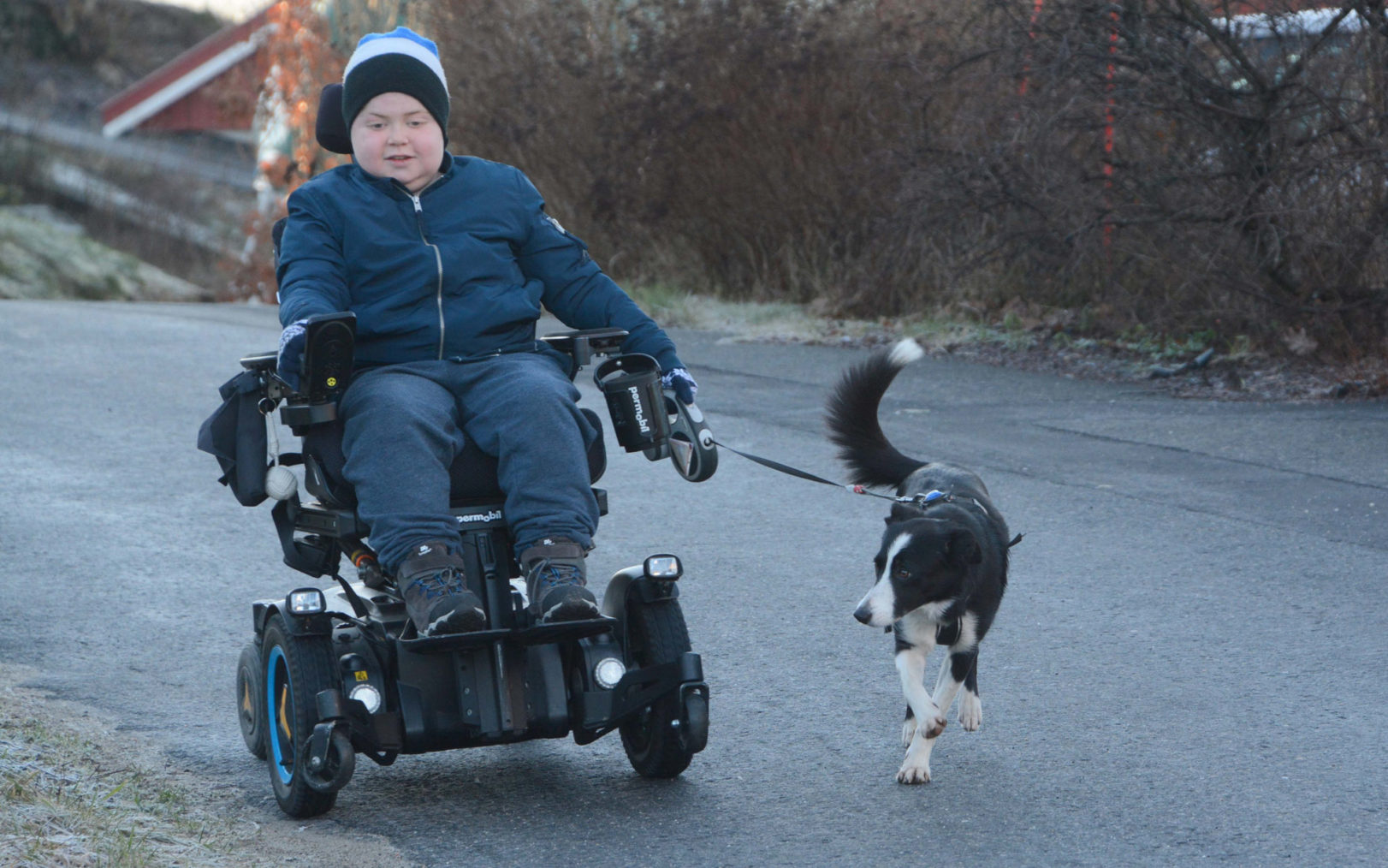 Andreas kjører rullestol, hunden løper ved siden av.