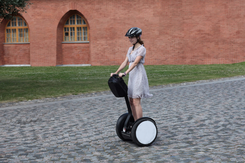 Kvinne kjører Segway på brosteinsbelagt gate.