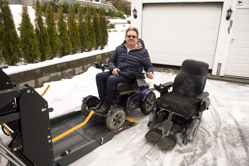Hansen med to rullestoler ved rampa bak på bilen.