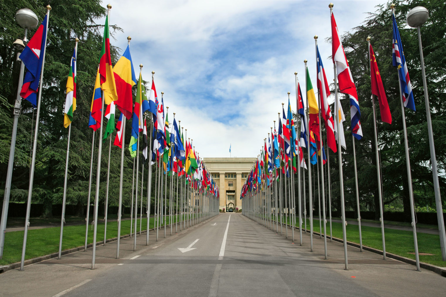 Bilde av veien inn mot inngangen til FN-bygningen i Geneve, kantet med flagg.