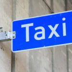 Bilde av skilt med teksten «Taxi» på en husvegg.
