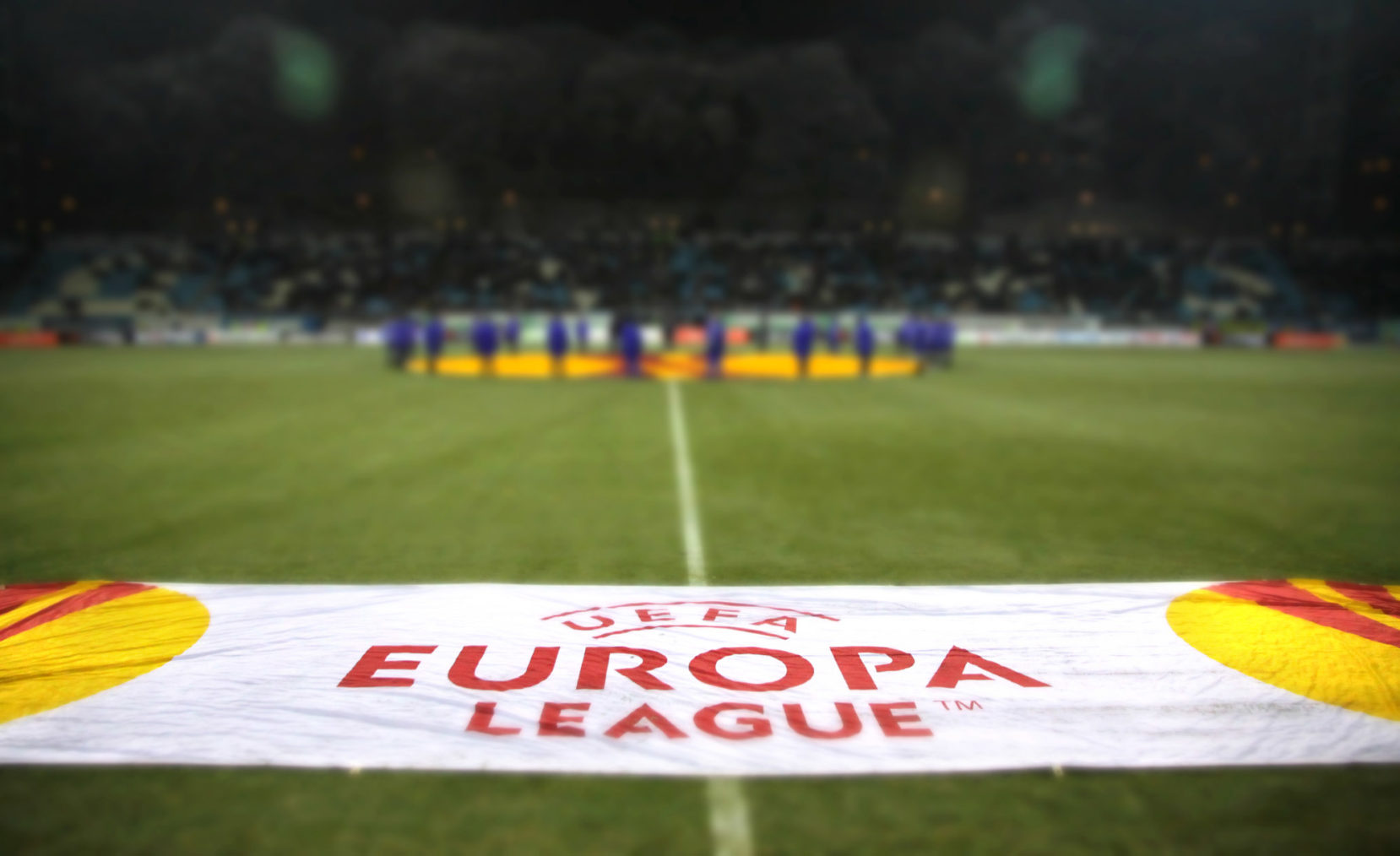 UEFA-banner på en fotballbane med tribune uskarpt i bakgrunnen.