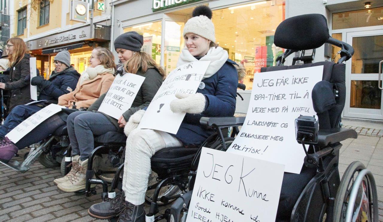 NHFU-aksjonister i rullestoler holder opp plakater.