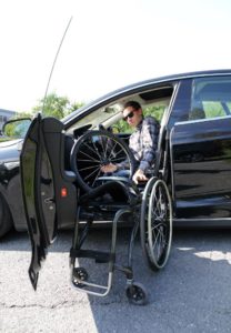 Adrian løfter rullestolen ut av bilen og setter på hjulene.