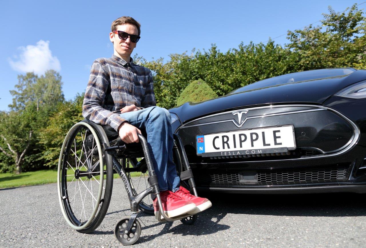 Adrian i rullestol ved bilskiltet «CRIPPLE»