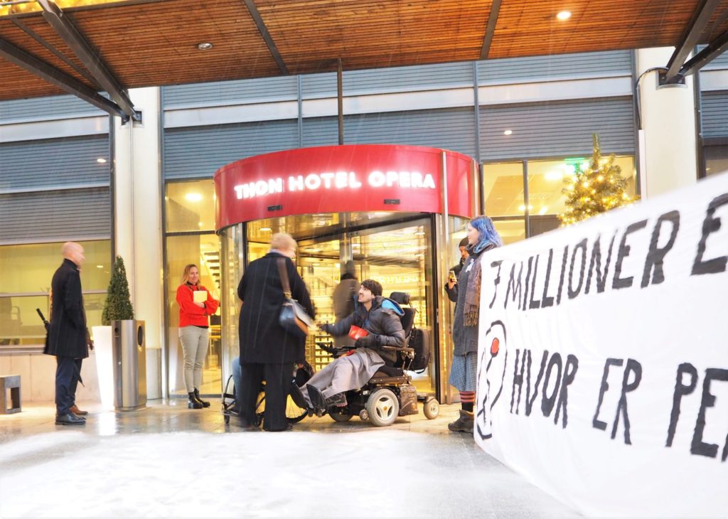 Demonstranter utenfor hotellets inngang holder opp plakater mens Grande går inn.