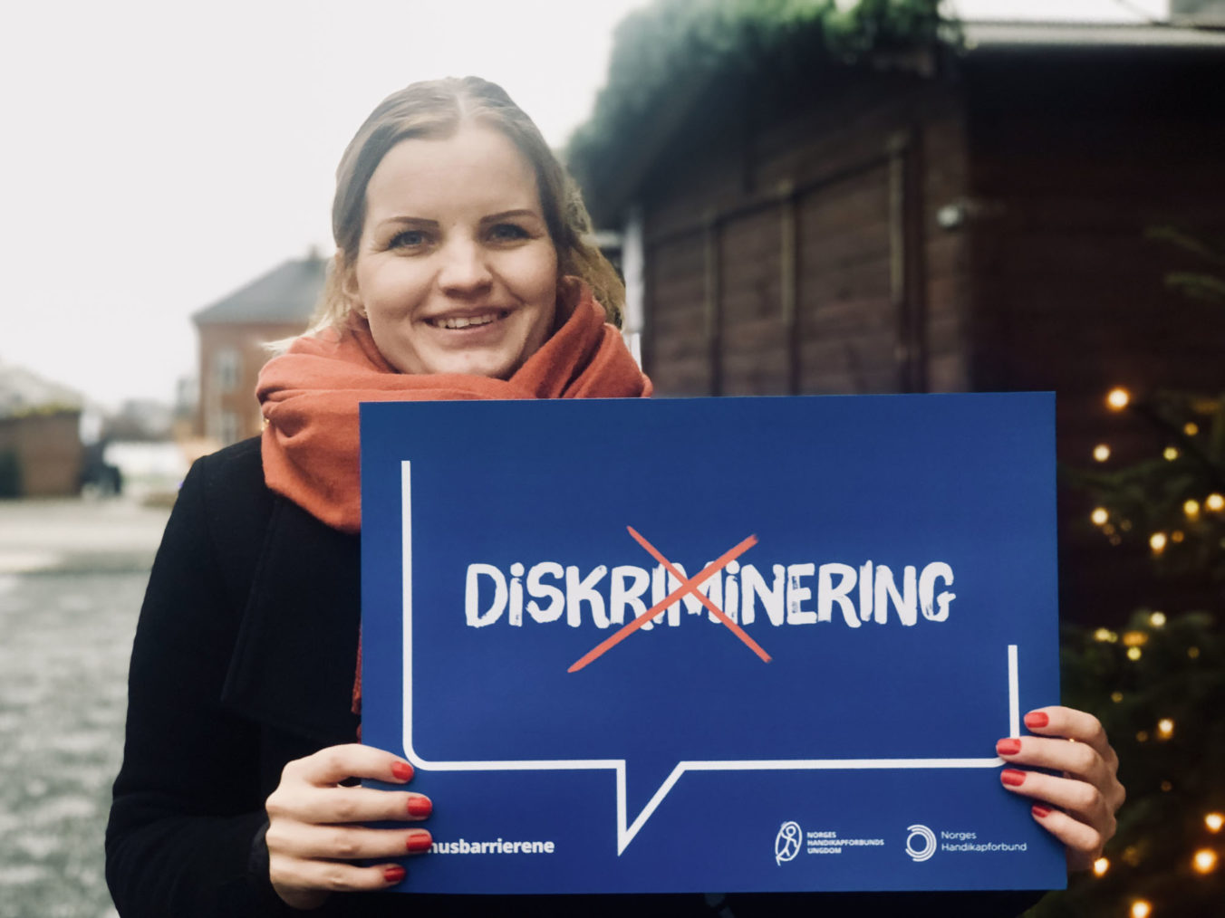Celina Hagen holde opp en plakat der ordet "diskriminering" er streket over.