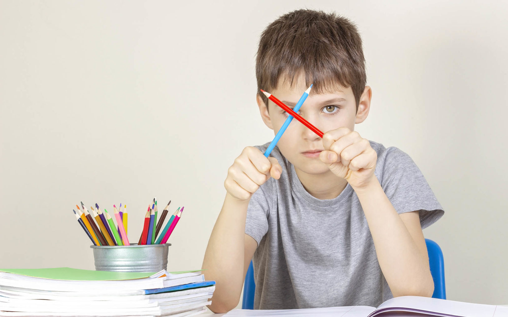bilde av skolegutt som holder to blyanter i kryss foran ansiktet.