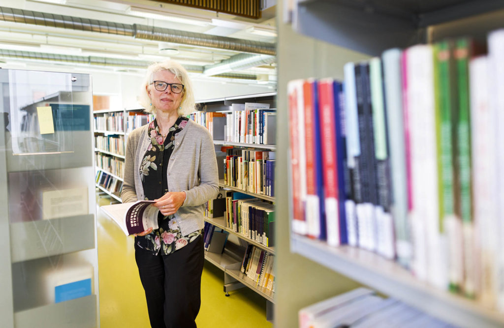 Portrett av Inger Marie Lid i et bibliotek.