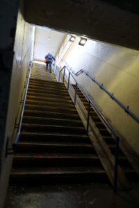 Lang trapp i tunnelen sett nedenfra. Øverst er det en person som går oppover trappen.