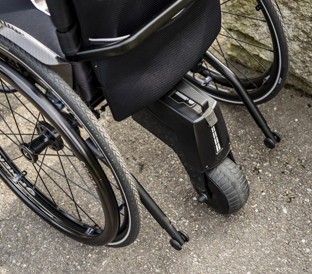 Nærbilde av drivaggregat montert på en manuell rullestol.