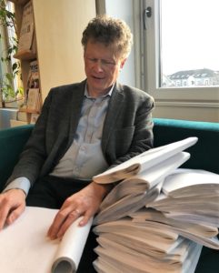 Sverre Fuglerud sitter ved en dokumentbunke og leser punktskrift.
