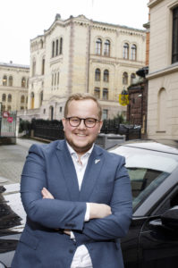 Eirik Faret Sakariassen poserer ved bil foran stortinget.