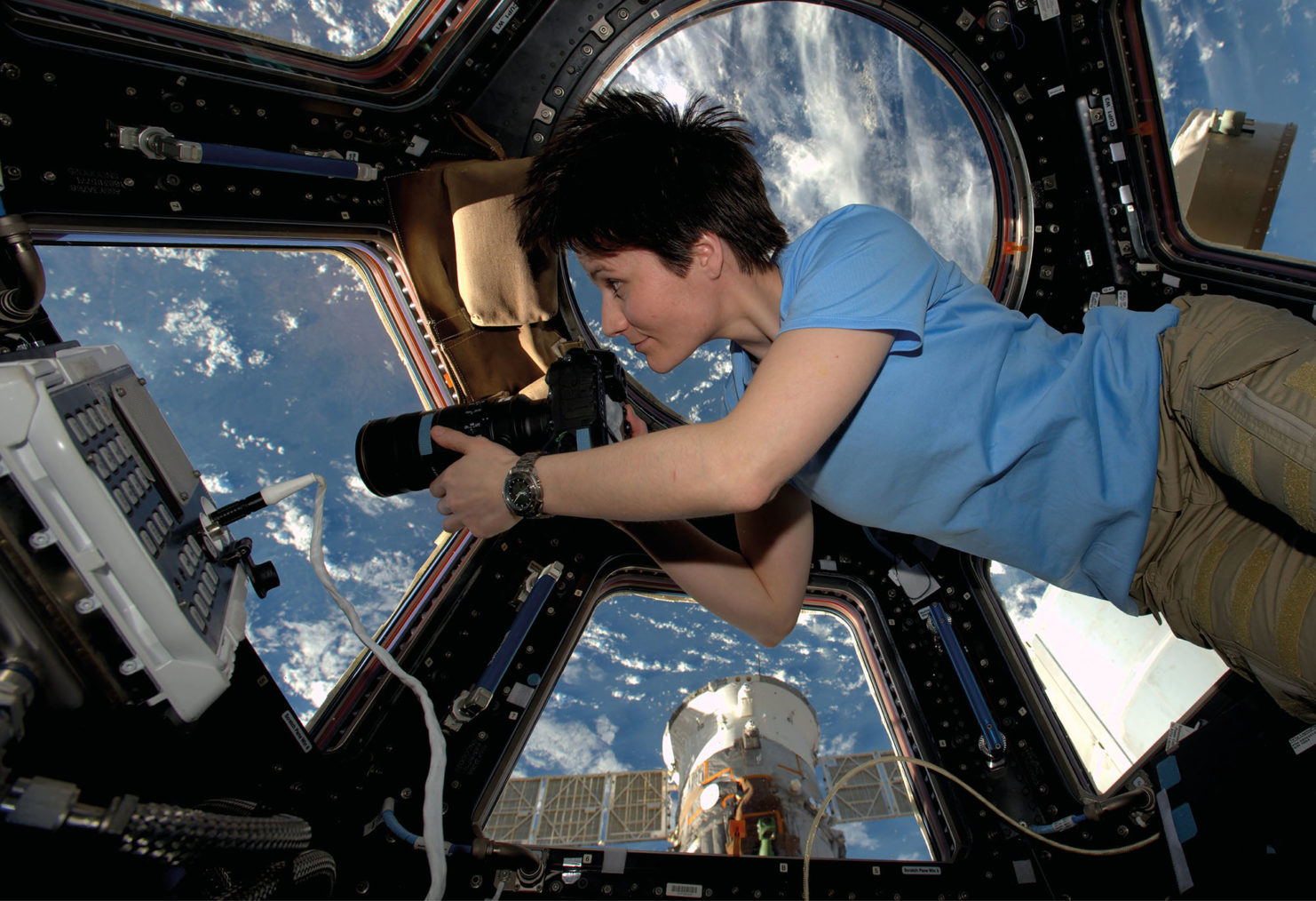 astronauten med kamera ser ut gjennom vinduet og ned på jorden.