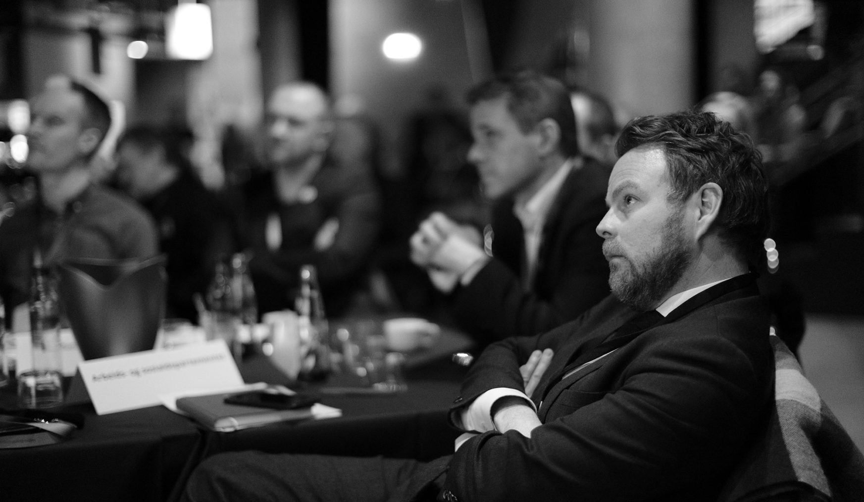 Torbjørn Røe Isaksen sitter tilbakelent og lytter til et innlegg på en konferanse.