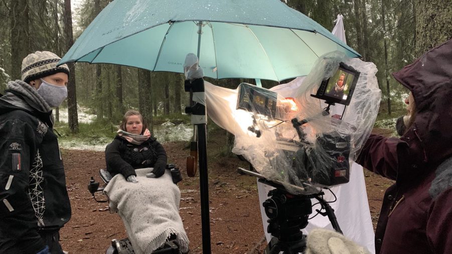 Bilde fra filmsett i skogen. Paraply over kameraet. Lena i rullestol.