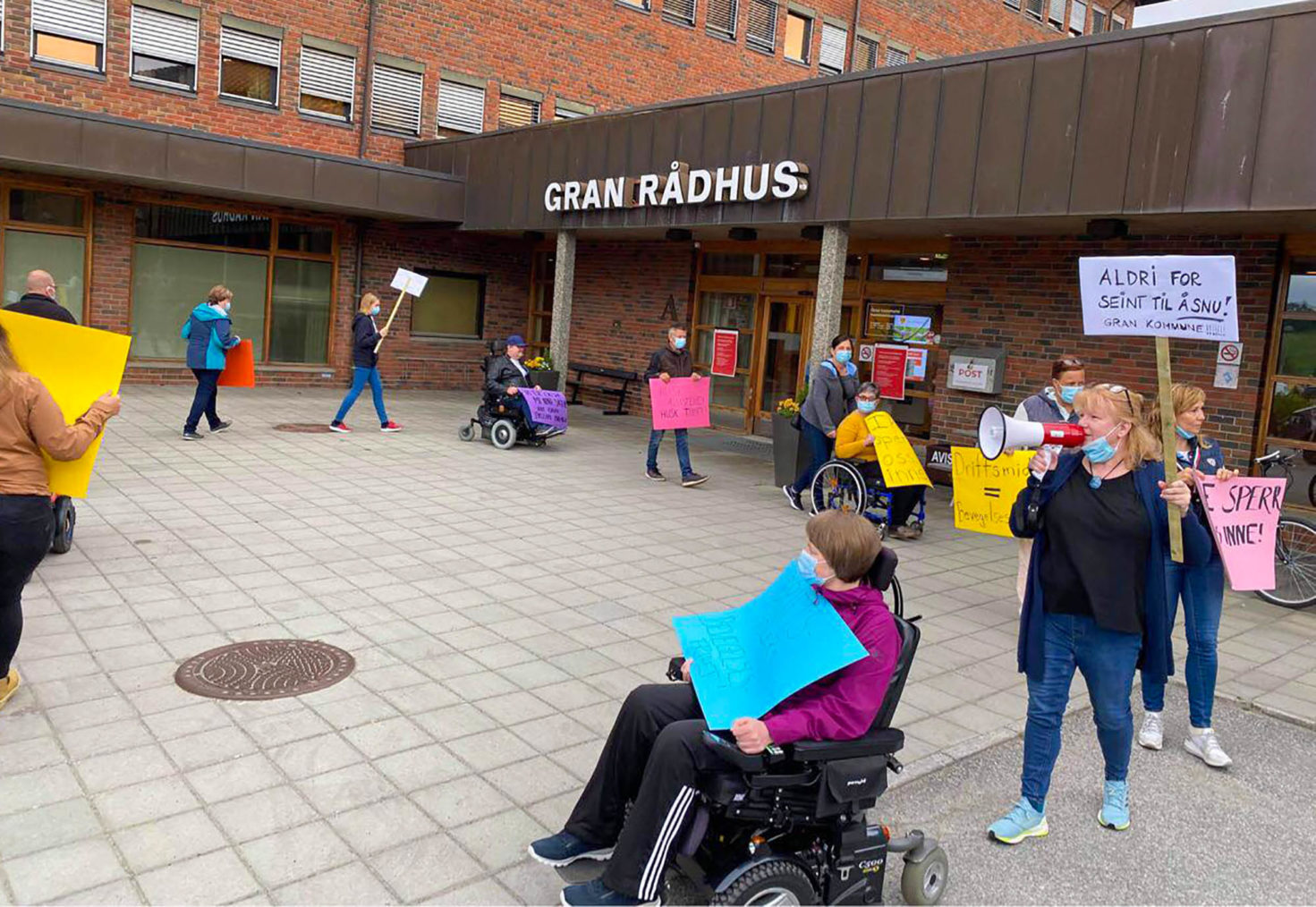 Demonstranter med plakater utenfor inngangen til Gran rådhus.