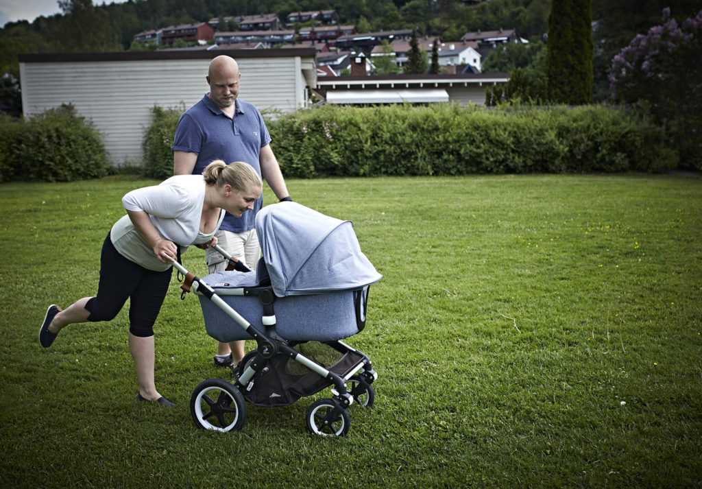 Ida og Thomas med barnevogn. Hun bøyer seg over vognen og titter ned på Tiril.