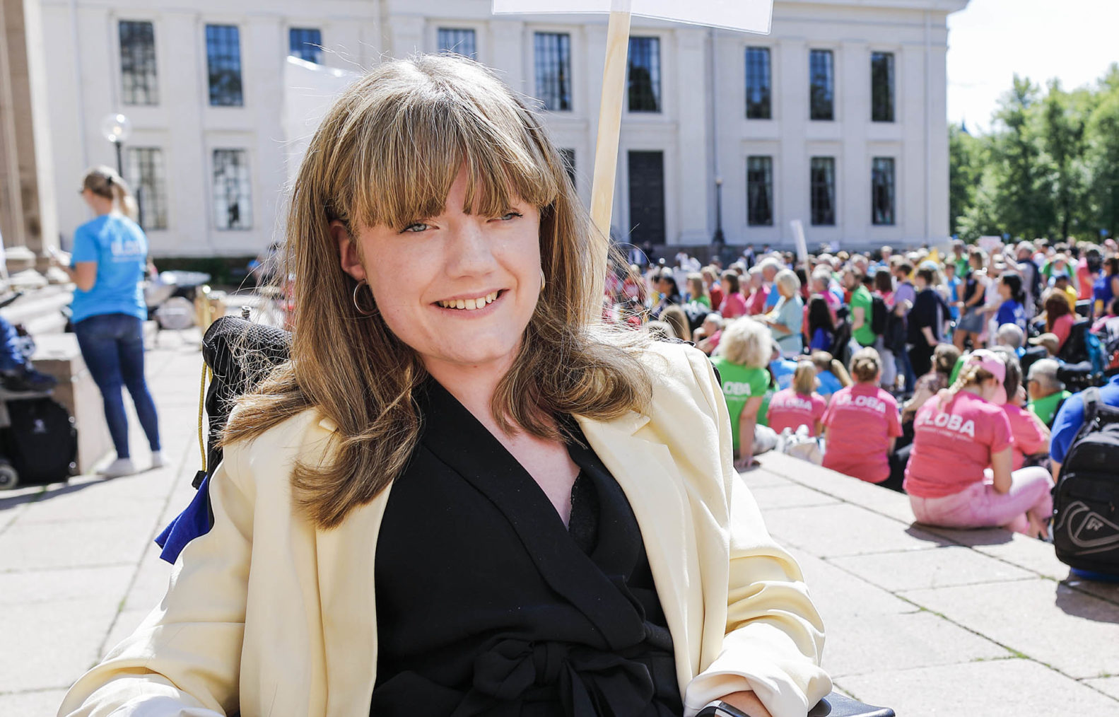 Portrettfoto av Marianne Knudsen, tatt på Universitetsplassen med masse demonstrerende mennesker i bakgrunnen.