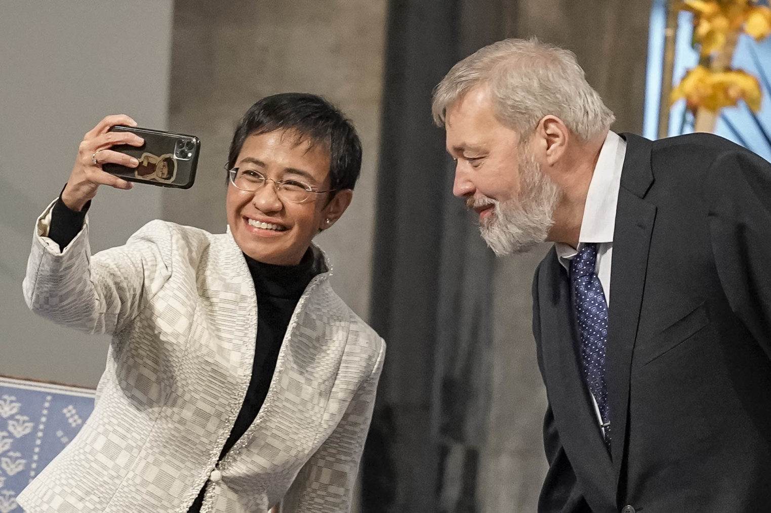 De to nobelprisvinnerne sammen i rådhuset. Hun holder opp telefonen og tar en selfie av dem begge.