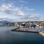 Utsikt over Tromsø med havnen, sjøen og fjell i bakgrunnen.