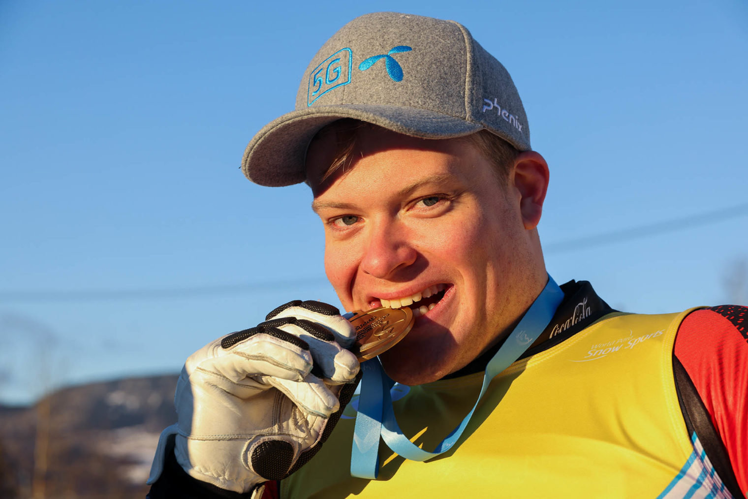 Jesper Saltvik Pedersen biter i en gullmedalje og ser smilende i kamera.