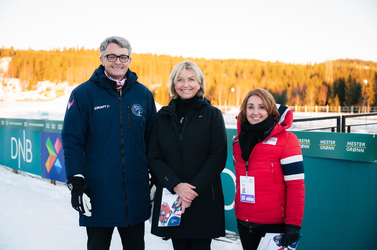 De tre sammen med skianlegg i bakgrunnen.