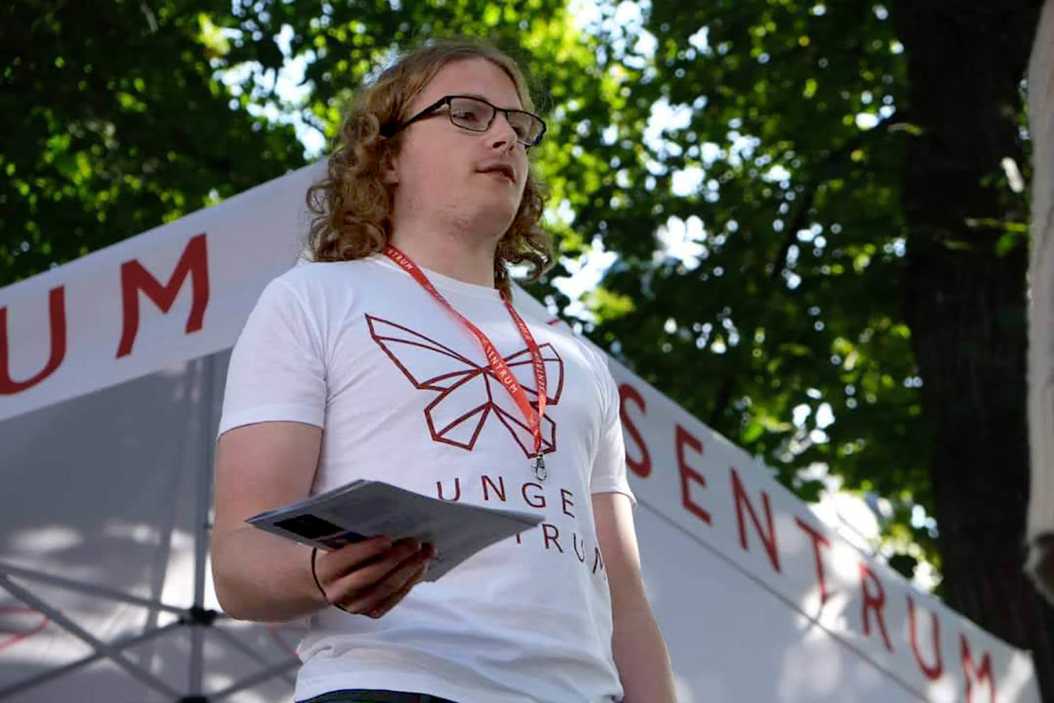 Bilde av Simen Bondevik som står på en stand for partiet Sentrum og deler ut løpesedler. Han har på seg en T-skjorte med Sentrums logo.