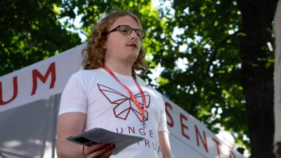 Bilde av Simen Bondevik som står på en stand for partiet Sentrum og deler ut løpesedler. Han har på seg en T-skjorte med Sentrums logo.