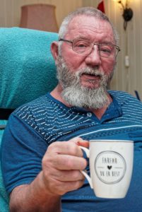 Portrett av Ole Martin Nordby som holder et kaffekrus med teksten «Farfar – du er best».